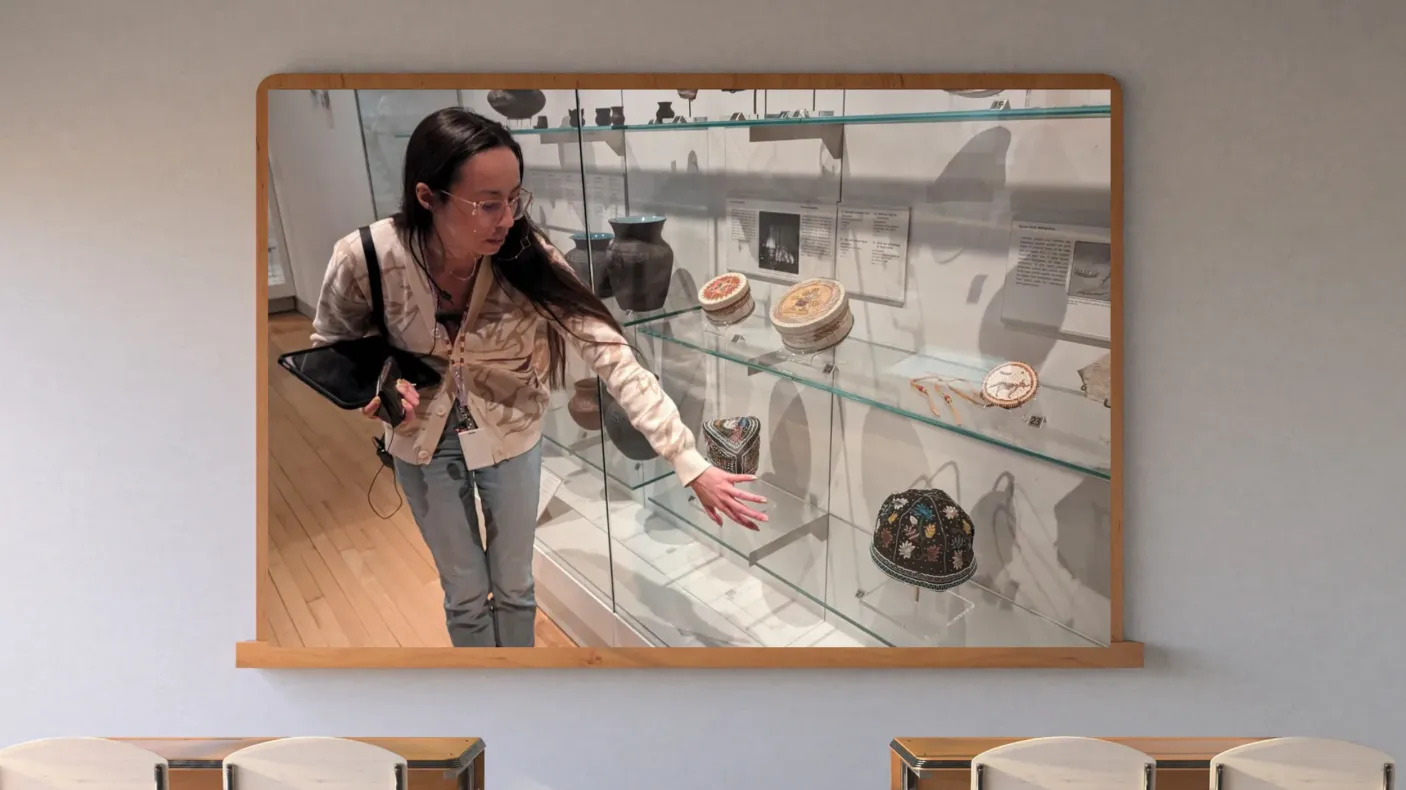 A screen on a classroom wall shows an Indigenous Museum Educator in the First Peoples Gallery at ROM