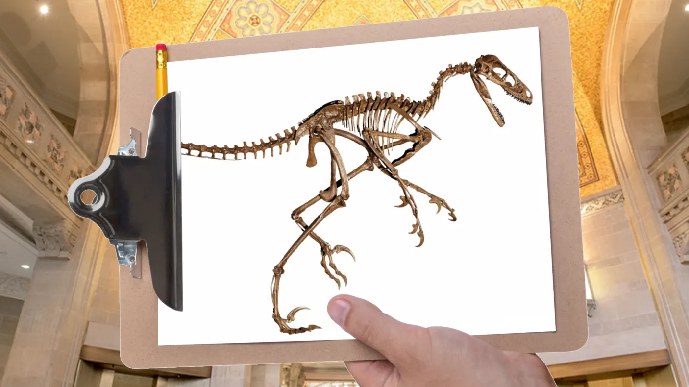 A hand holds a clipboard in front of a gallery with a mosaic ceiling. The clipboard is holding a picture of a raptor dinosaur skeleton.