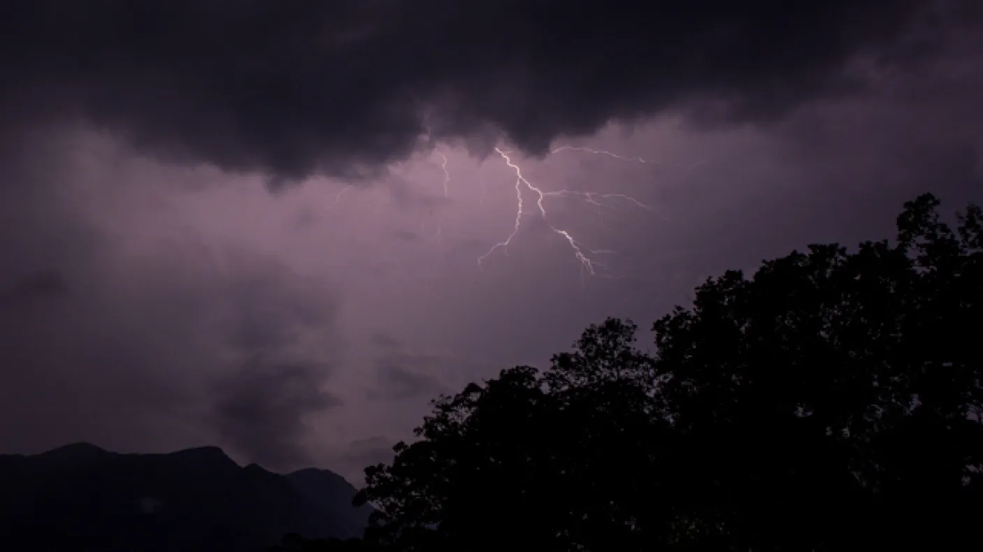 A bolt of lightning streaks across a purple sky over the mountains and rainforests of Sri Lanka
