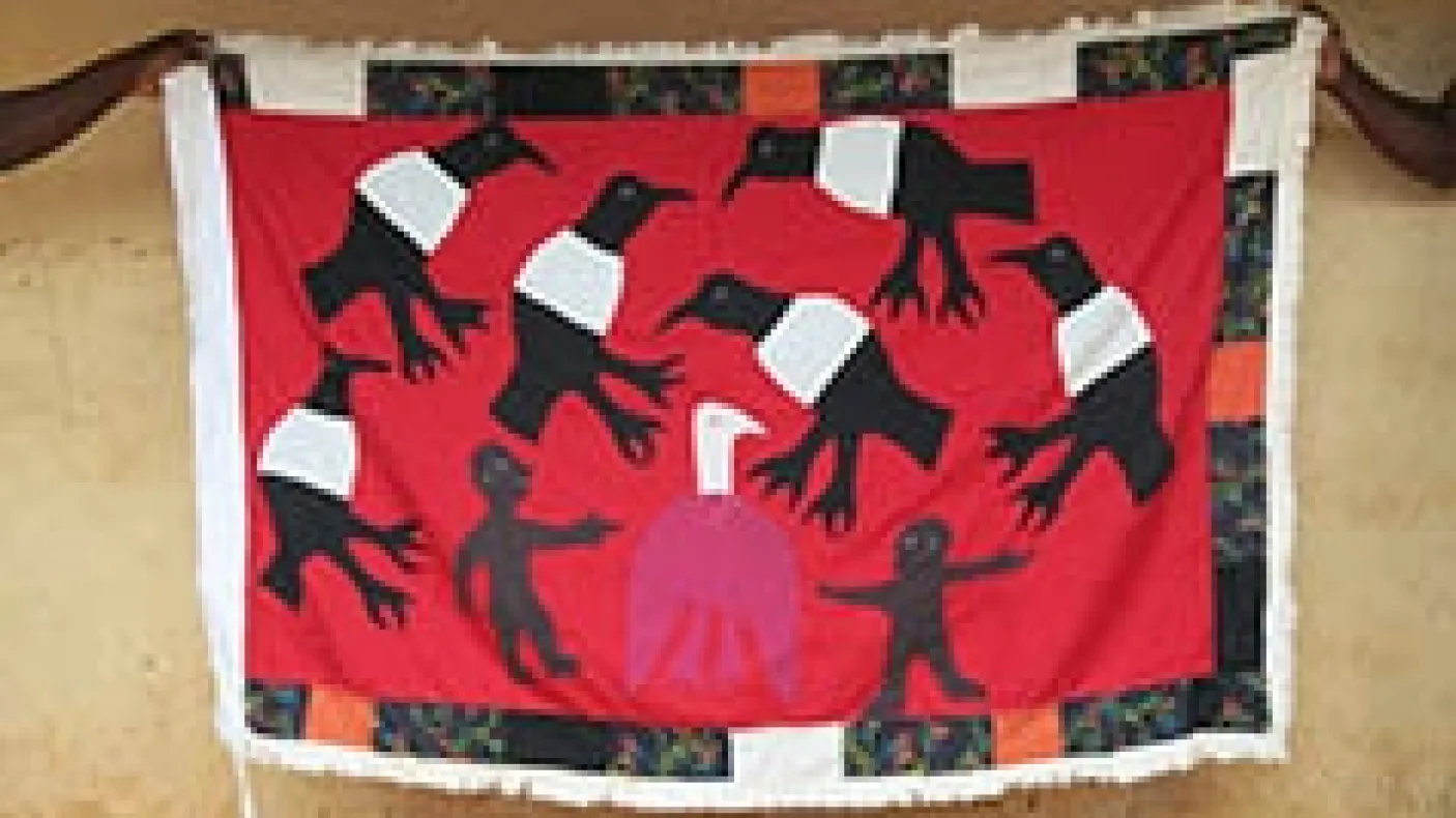 People holding up a handmade flag depicting birds.
