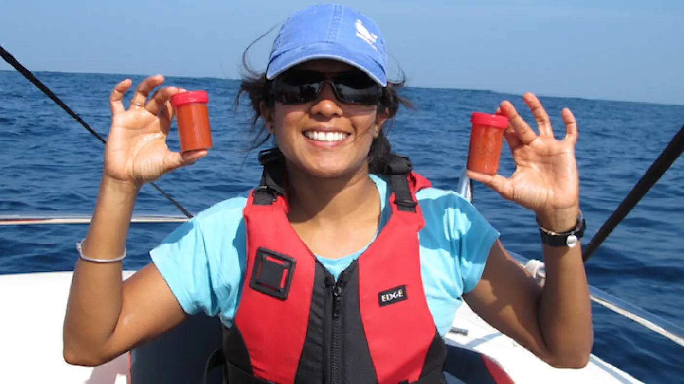 Asha de Vos, P.h.D. holds two bottles of freshly collected blue whale poop off the coast of Sri Lanka. Photo Credit: Oceanswell
