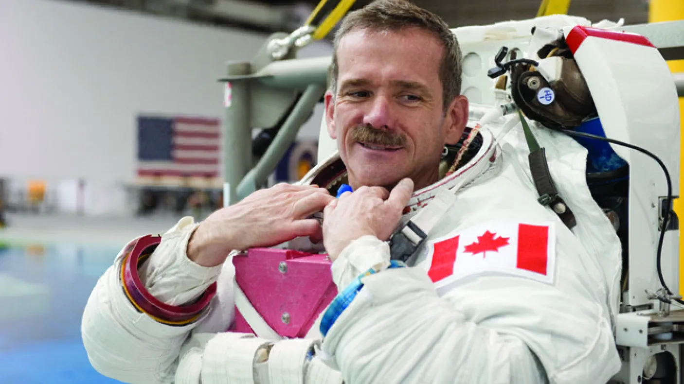 A photograph of a man in an astronaut suit without a helmet
