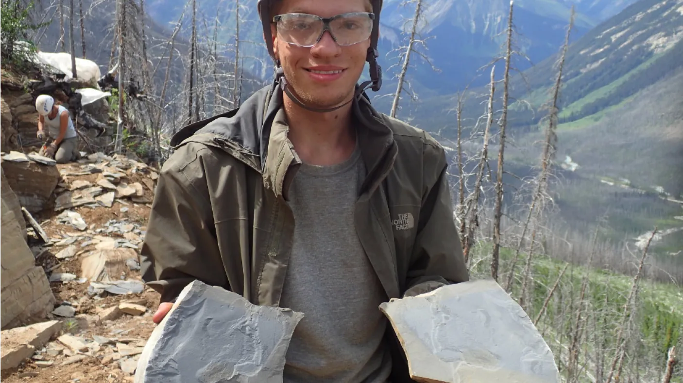 Un étudiant tient des plaques de schiste contenant des fossiles.
