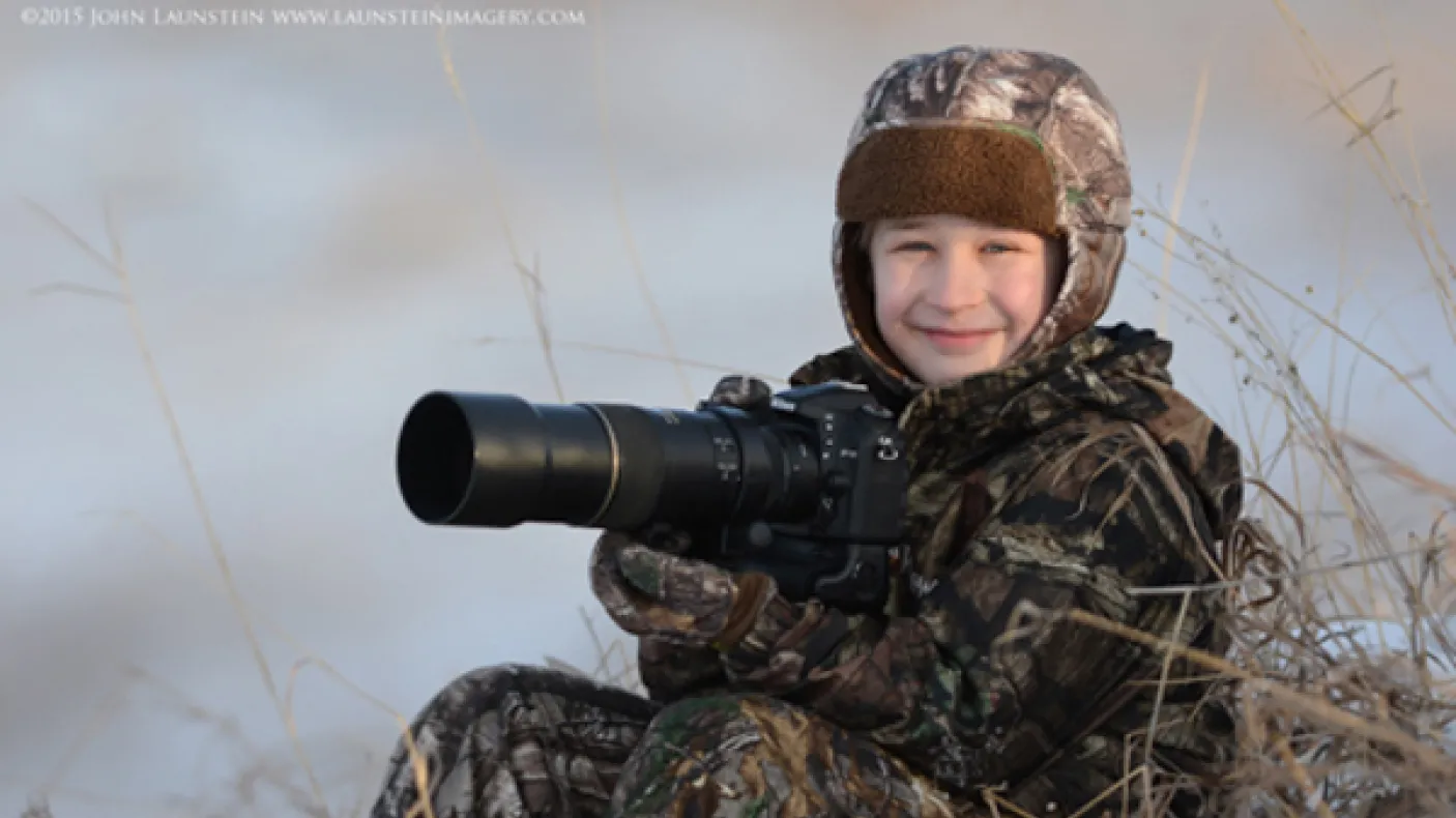Ten-year-old wildlife photographer Josiah Launstein sits bundled up and ready to take the shot.
