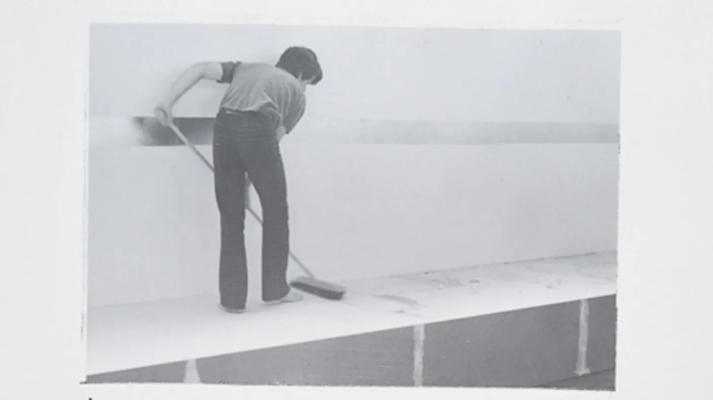 Black and white photo of a man mopping a platform
