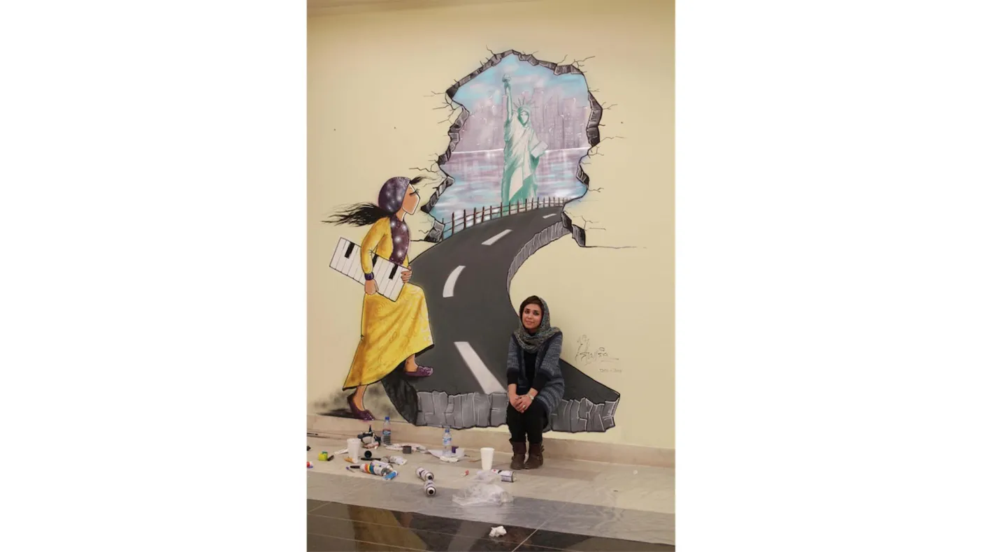 Shamsia Hassani devant l'une de ses peintures murales