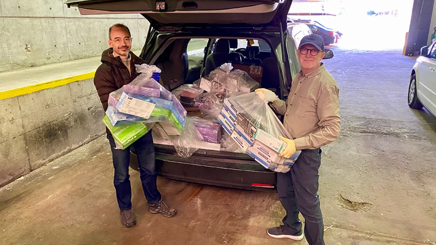 Two ROM staff load an SUV with PPE.