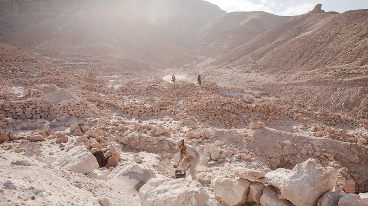 Three archaeologists working in a valley.
