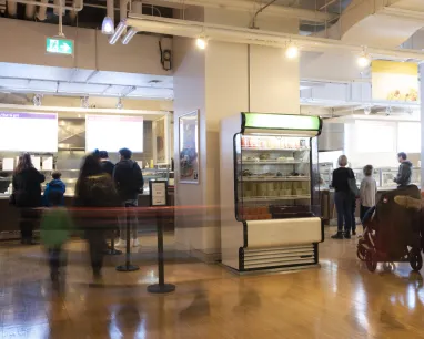 People line up for food in a bustling cafe.