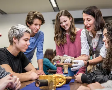 Students gathered around table with instruction holding tiger object