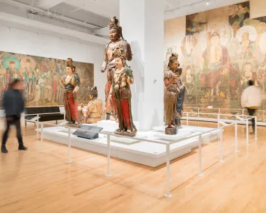 A spacious museum displays a large painting of Buddhas on the wall, highlighting their peaceful expressions and rich symbolism.