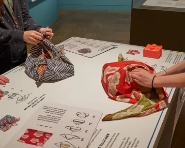 image of 2 ppl folding material over box in Shokkan