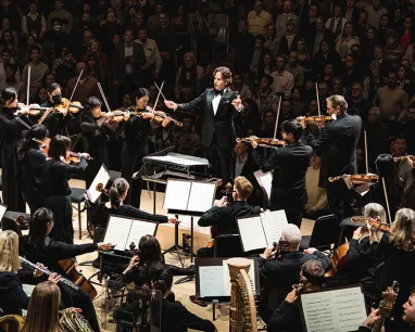 Toronto Symphony Orchestra performing on stage with conductor leading musicians.