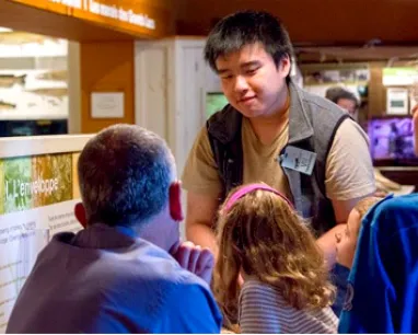 Volunteer speaking to a group of visitors in the Hands On Gallery