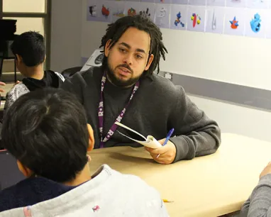 ROM intern talking with two elementary school students at a table