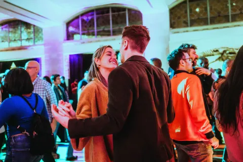 Couple locking hands in a crowd at a museum.