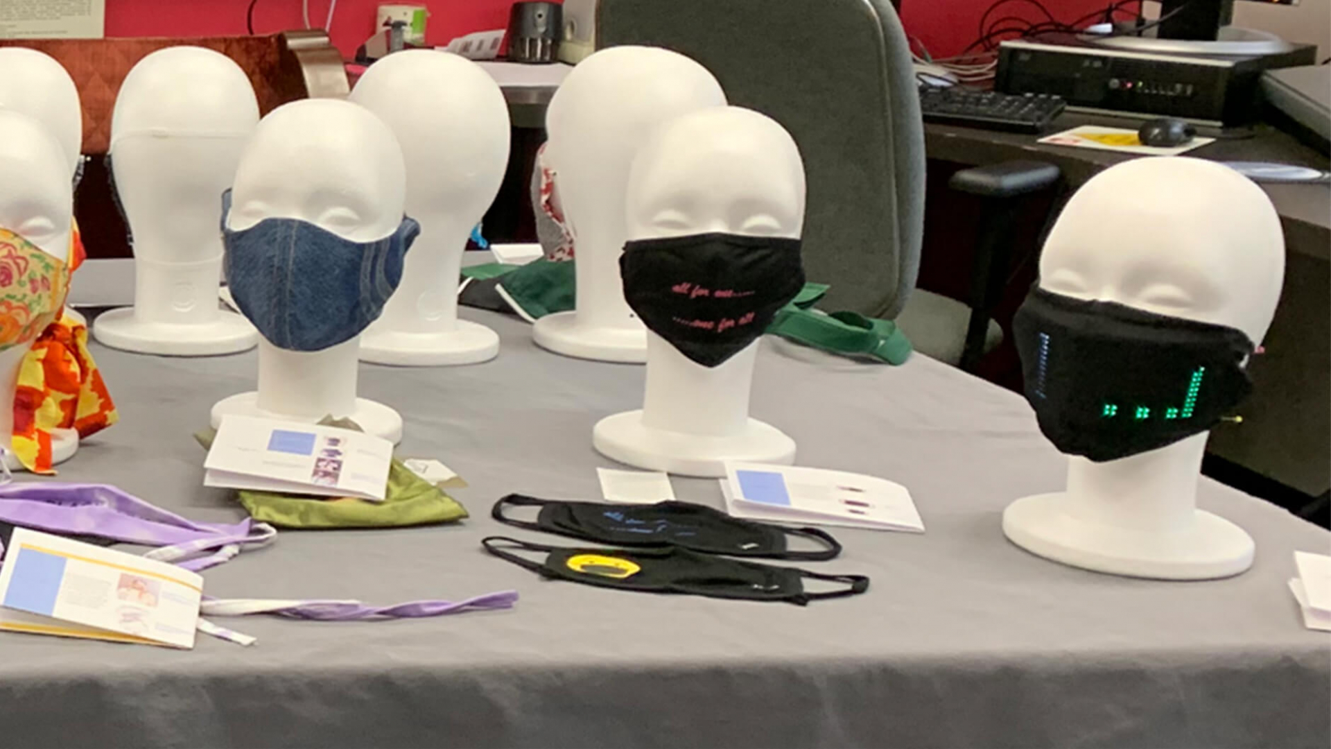 An array of mannequins on a table wearing face masks.