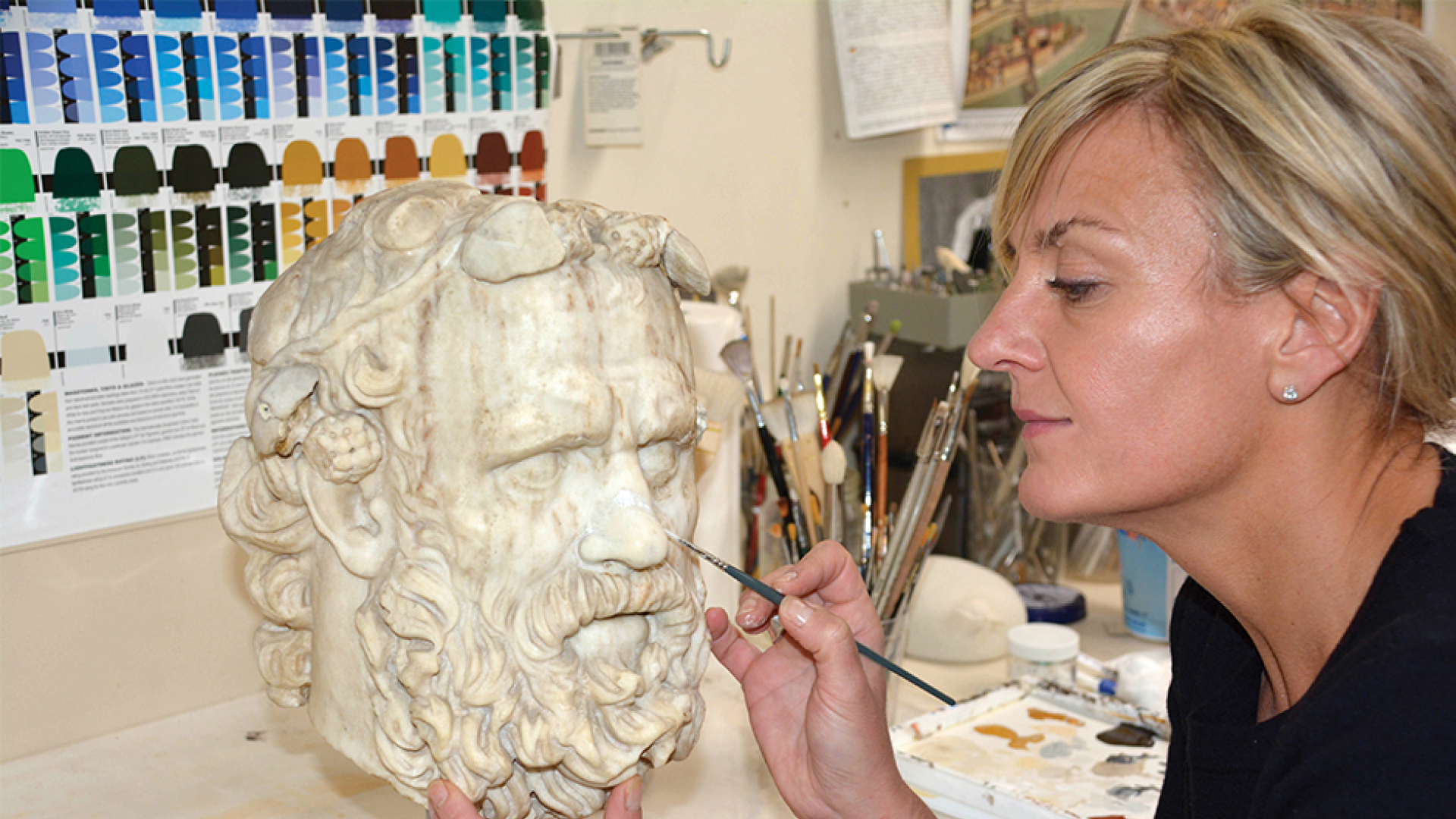 Laura Lipcei painting a Greek statue.