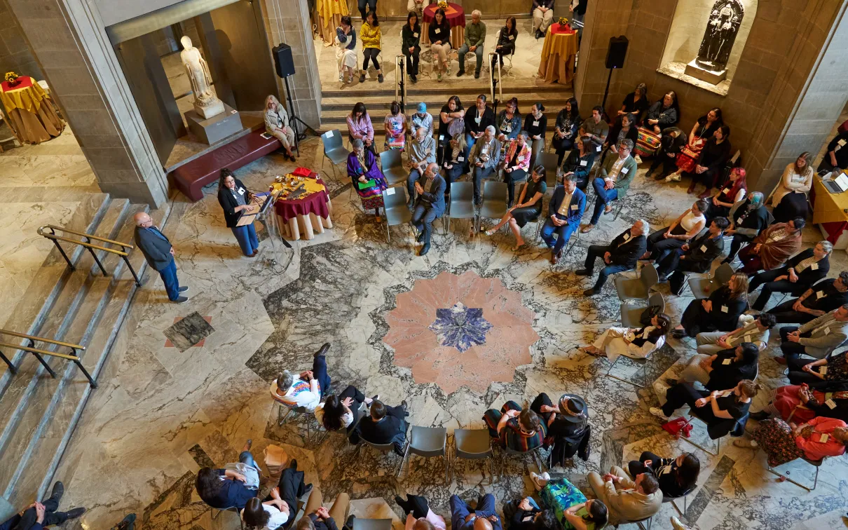 Presentation attendees in a large circle listening to a presentation.