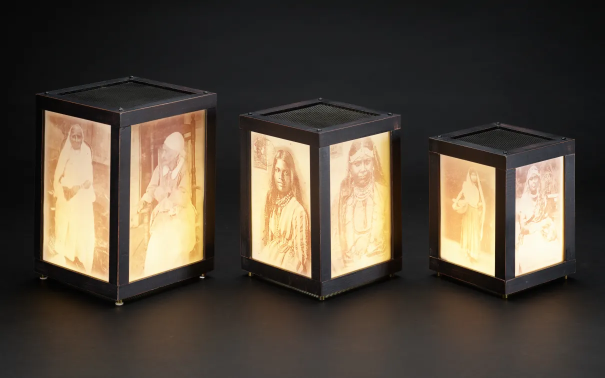 Three illuminated rectangular lanterns with images on the glass.