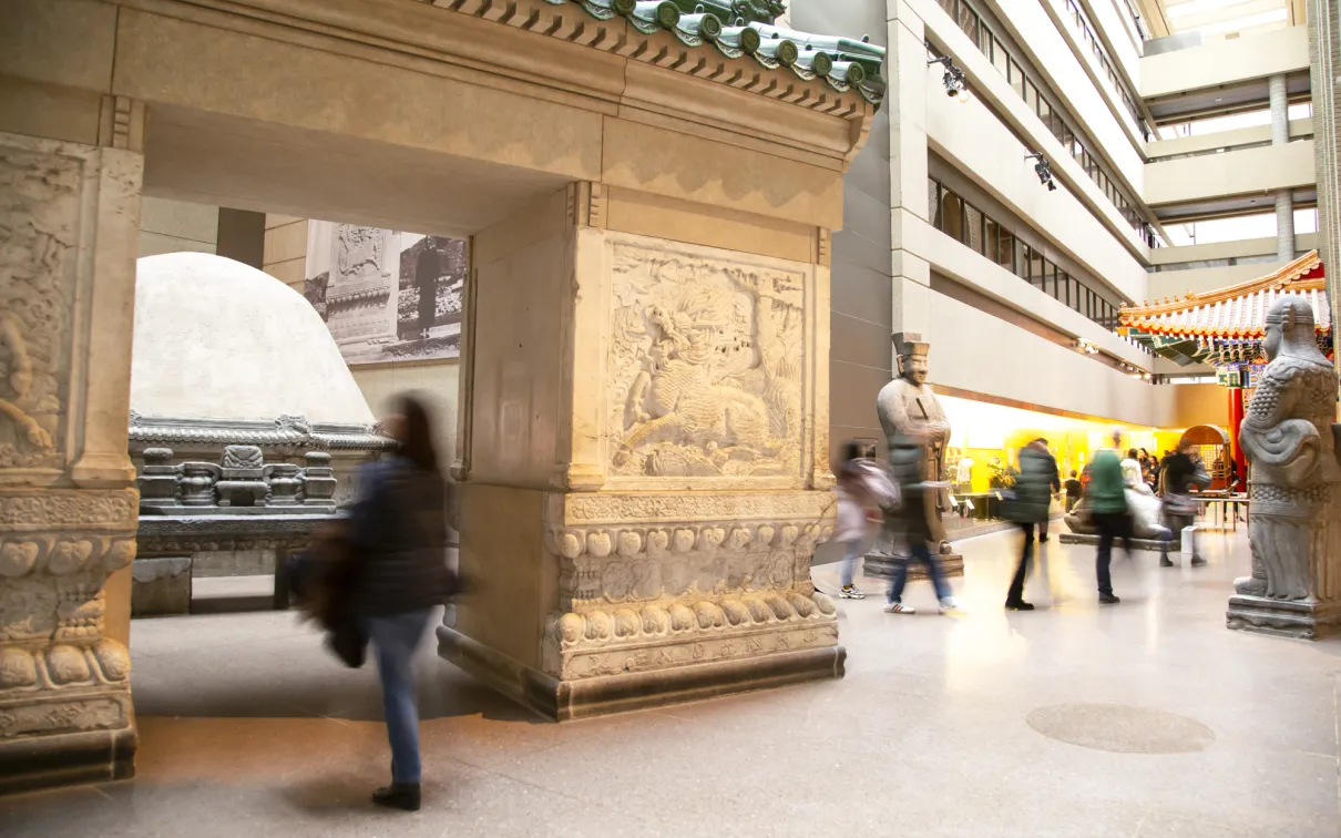People walk through a gallery with a large entry gate