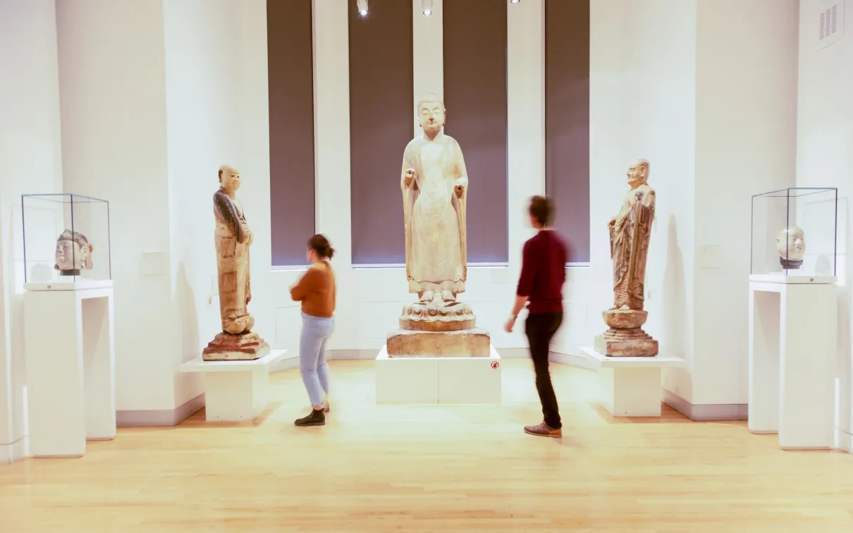 Two people look at three large Chinese sculptures.