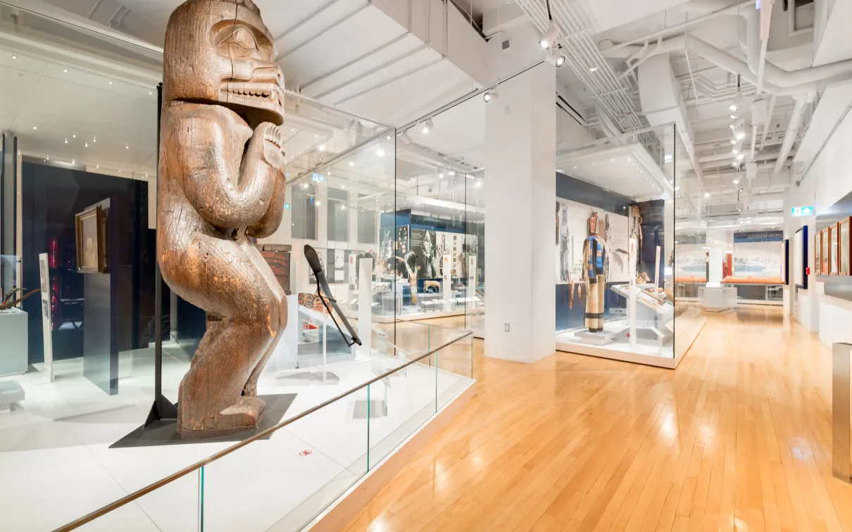 Une galerie avec, au premier plan, un grand poteau de maison en bois sculpté