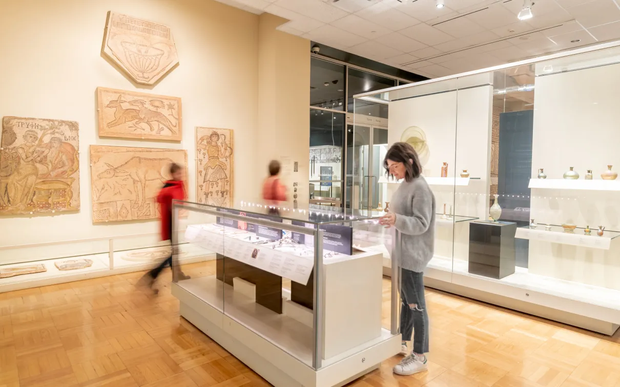 A person pauses to examine an object in a case.