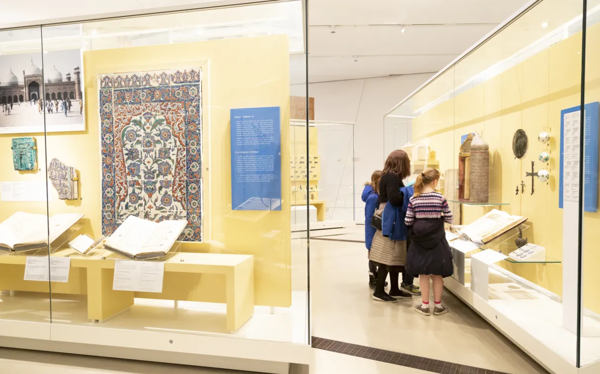 Une famille examine un objet du Moyen-Orient dans la vitrine d'une galerie.