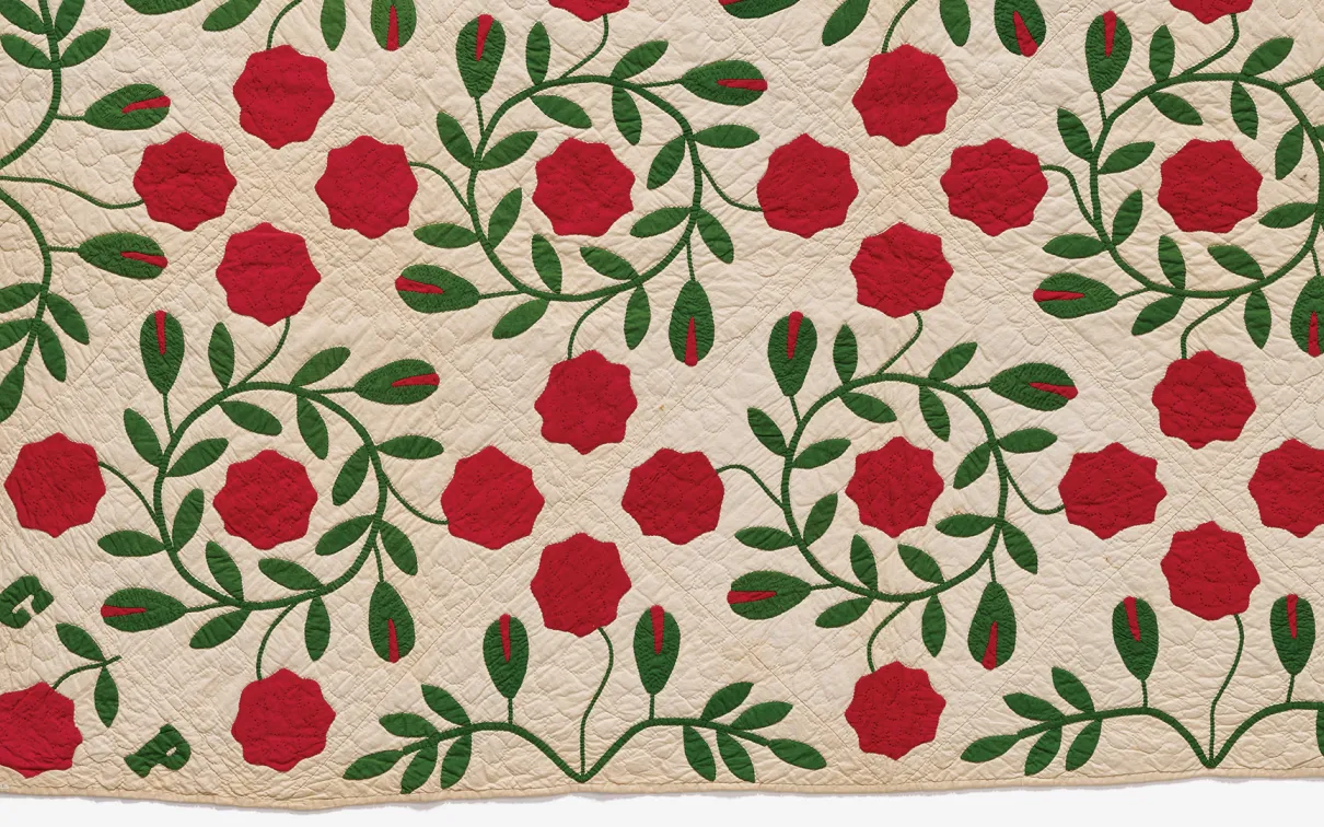  A beautifully crafted red rose quilt adorned with intricate green leaves, showcasing vibrant colors and elegant design.