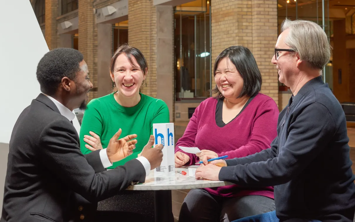 Four people stand around a table happily chatting
