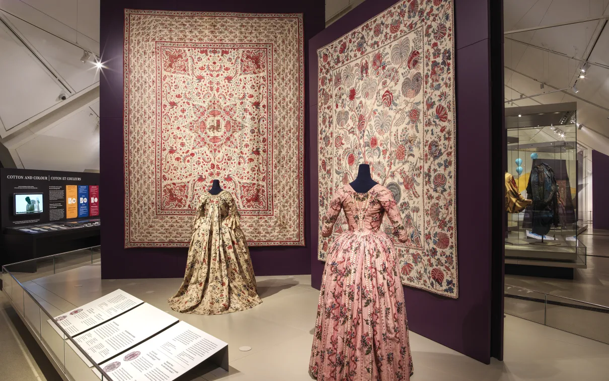 A display case featuring diverse clothing pieces and a book, illustrating a blend of style and reading material.