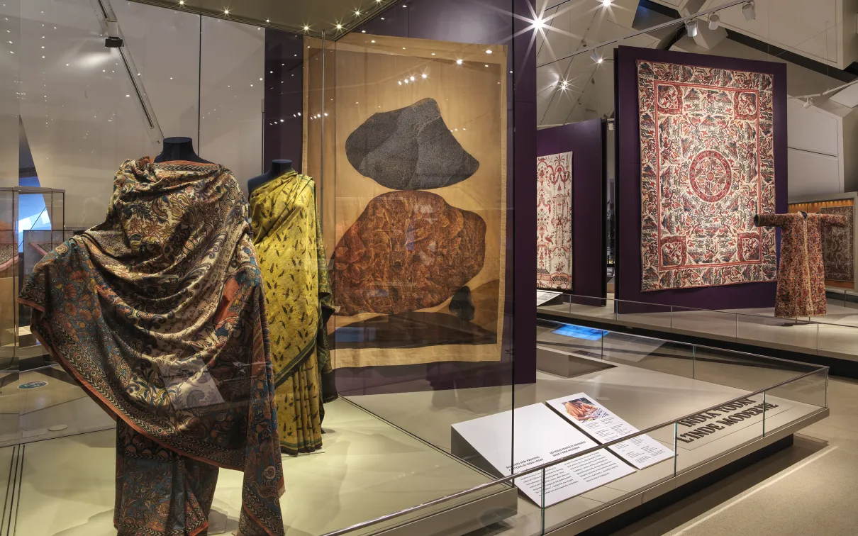 A display case featuring diverse clothing pieces and a book, illustrating a blend of style and reading material.