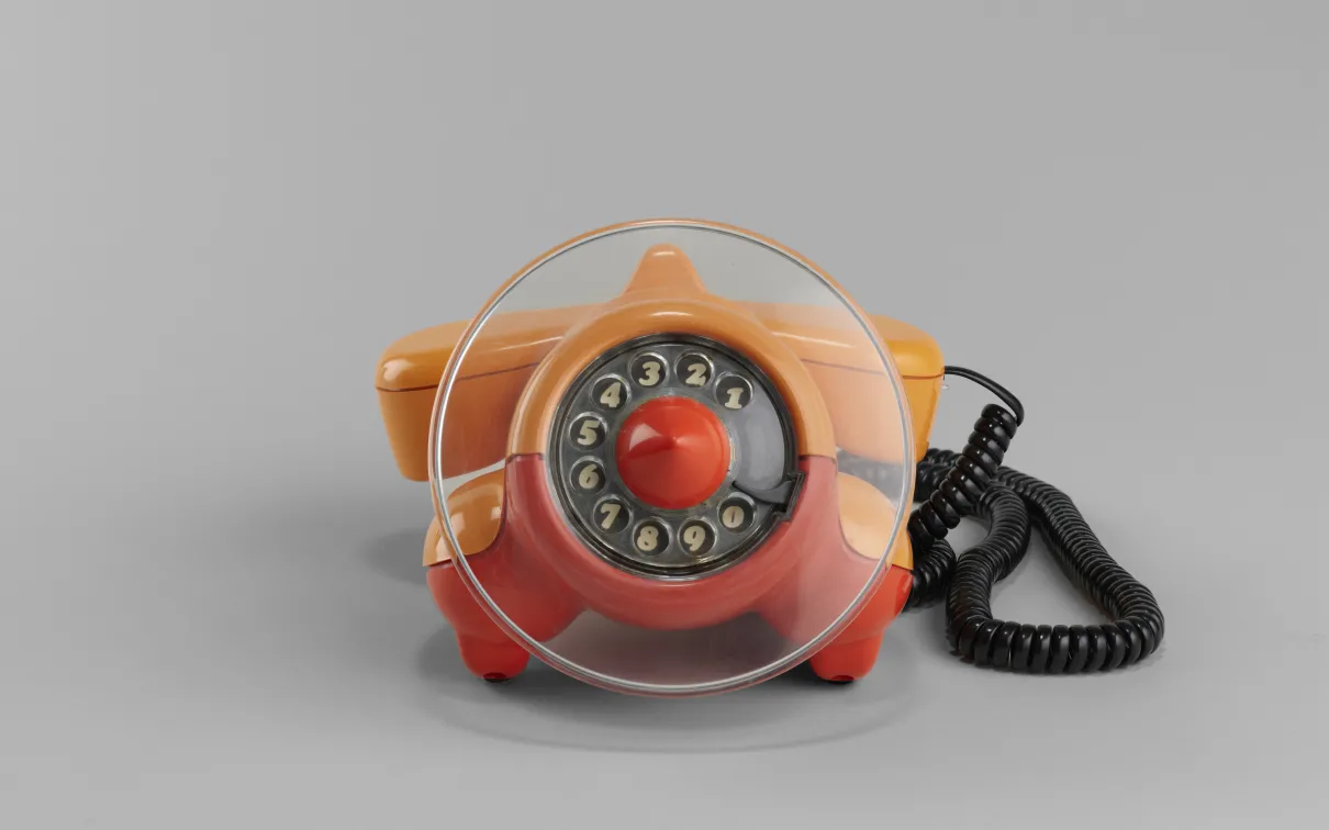 An orange and red corded telephone resting on a surface, showcasing its vibrant colors and classic design.