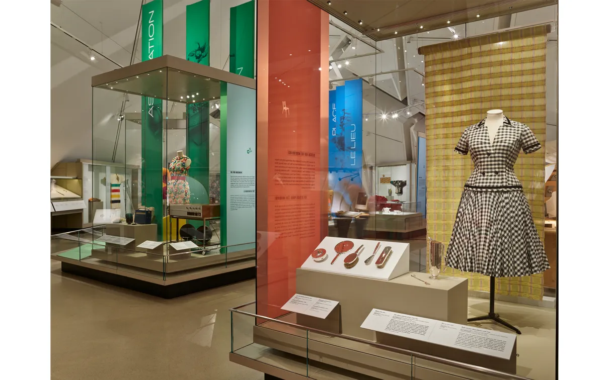 A display case showcasing an elegant dress alongside various complementary items, highlighting fashion and design.
