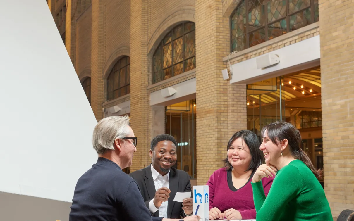four people sitting at a table, having a fun conversation practicing English at the Royal Ontario Museum
