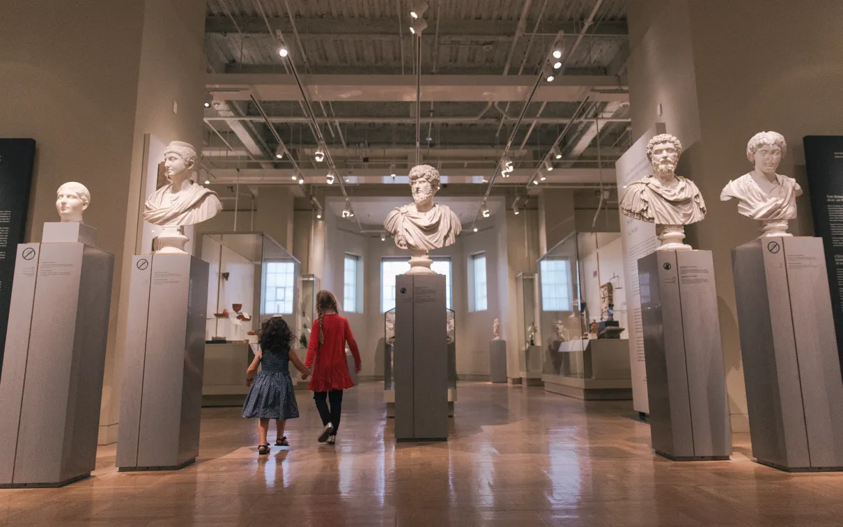 two people walking through the Roman portrait display in the Gallery of Rome.