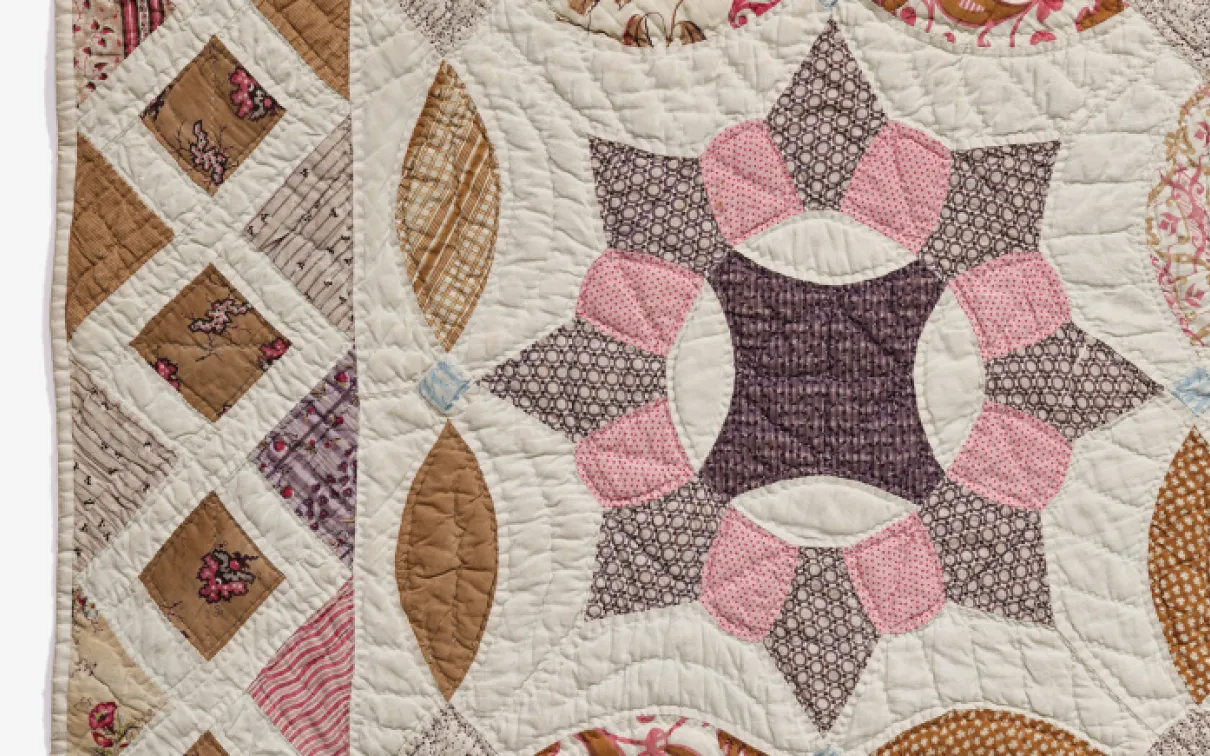 A close-up view of a quilt featuring an intricate design in shades of pink and brown.