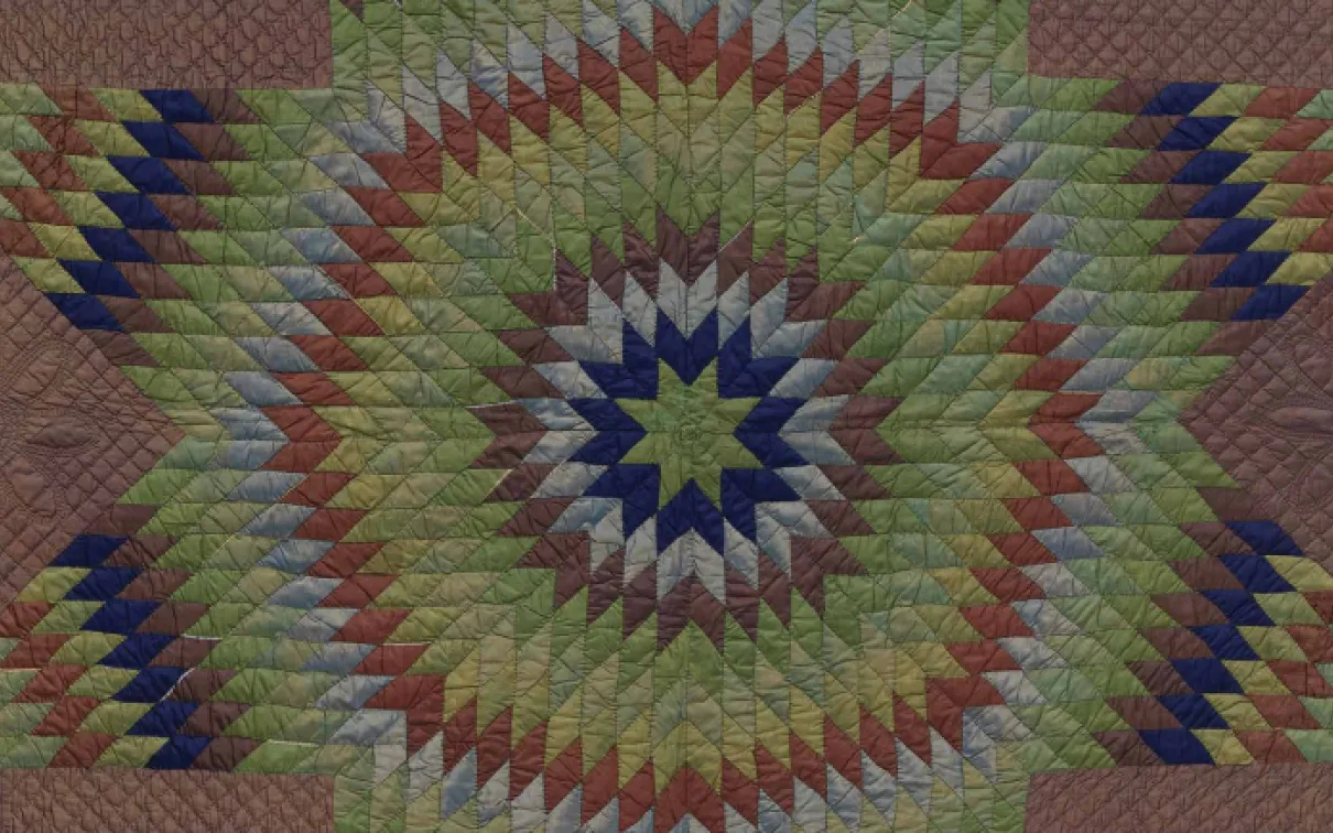 A star-shaped quilt with a striking green, blue, and red pattern, emphasizing its quilted texture and artistic design.