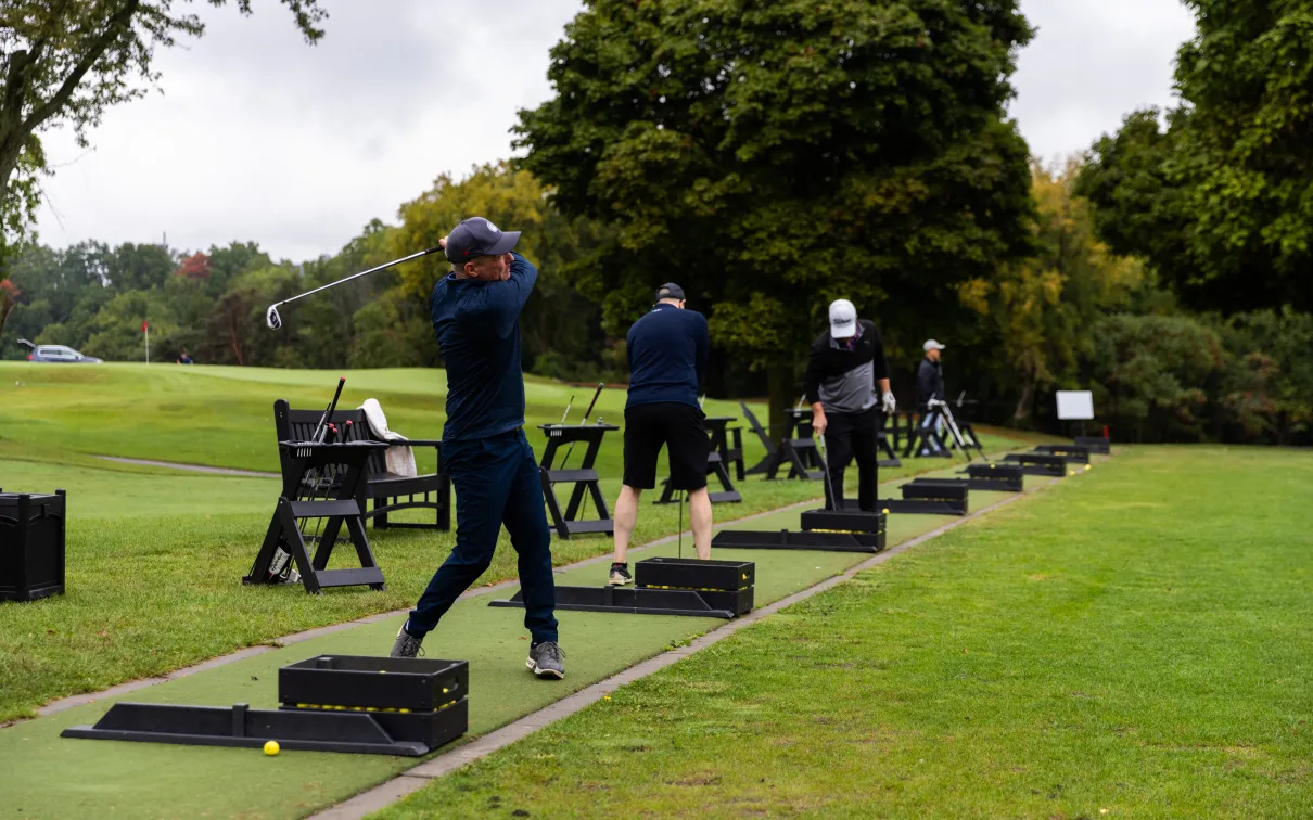 Male golfers on swinging their golf clubs on the driving range