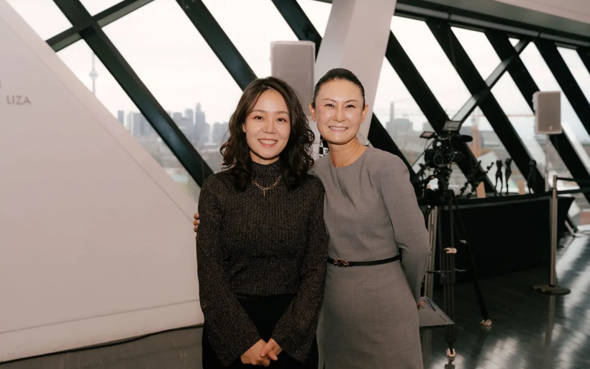 Two women, Hyon Chu Lee and Dr. Vicki Sung-yeon Kwon, stand side by side at the Korea Gallery gift announcement at the Royal Ontario Museum. Both are dressed formally and smiling warmly. The background features museum signage and elegant display cases.