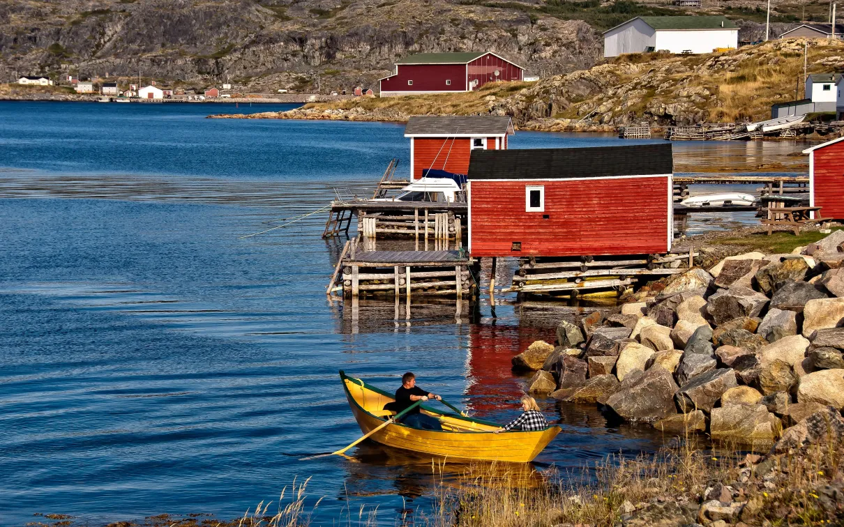 Colourful houses by the seacoast with a rowboat in the foreground.