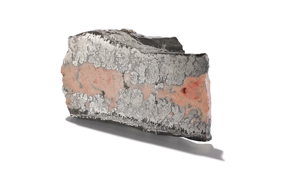 Cobalt (in smaltite from Temiskaming), Ontario, Canada. Image ©ROM. Pie-shaped sample of cobalt mineral encased in smaltite, shown on a white background.