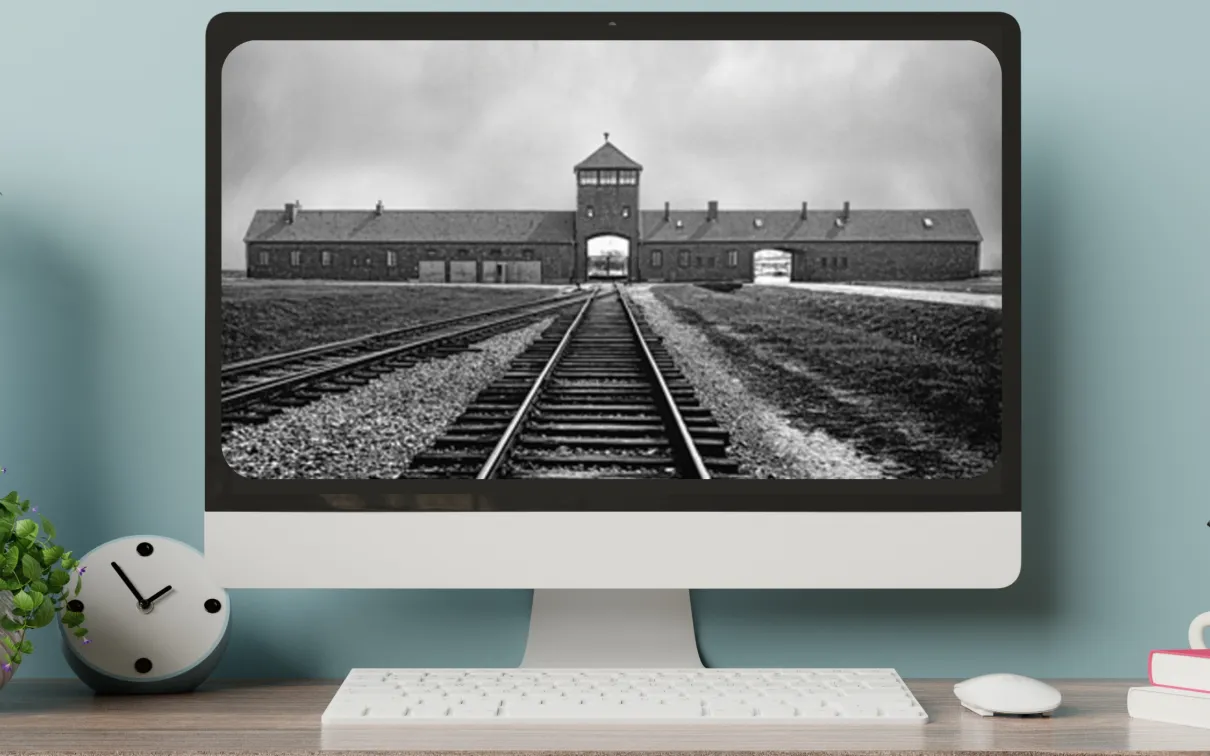 A computer on a desktop shows a black-and-white image railroad tracks leading toward an arched gate beneath a peaked tower.
