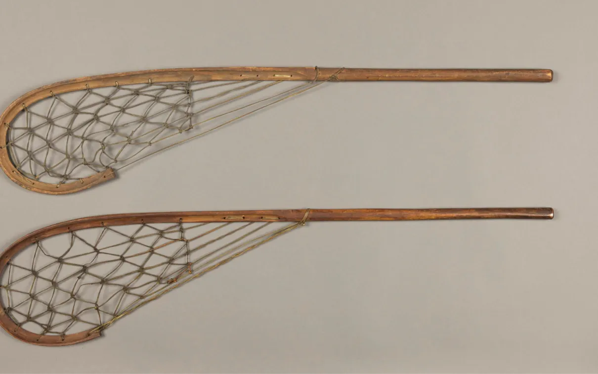 Two long wooden sticks that curve at the end. Within the curve, attaching to a point about midway down the stick, is a lattice of knotted strings made of hide.
