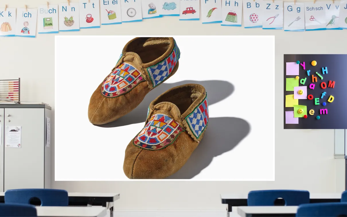 A screen in a colourful classroom displays a pair of beaded leather moccasins