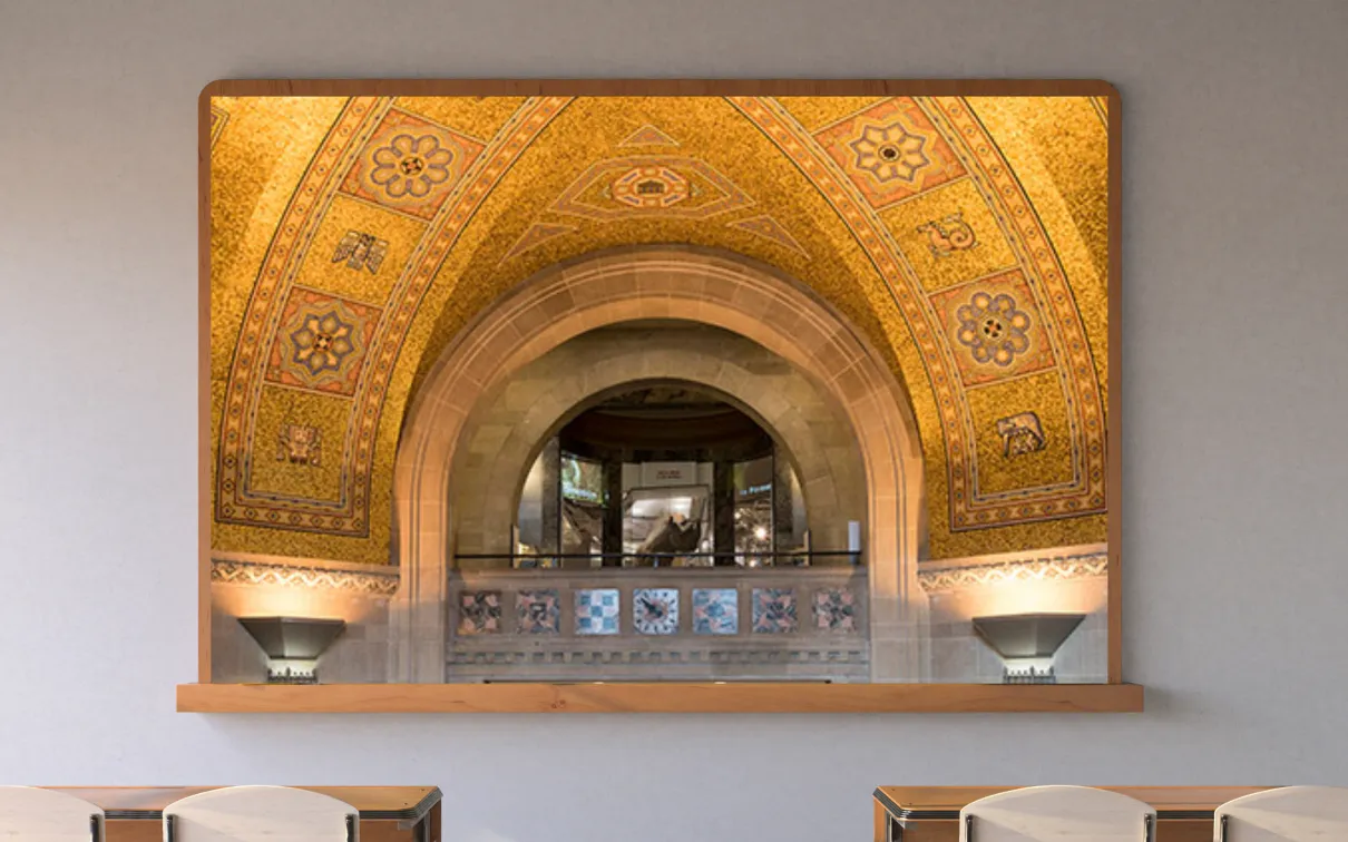 A screen in a classroom displays a balcony with an arched roof beneath a golden mosaic ceiling. A rhinoceros in a case is visible through the arch.