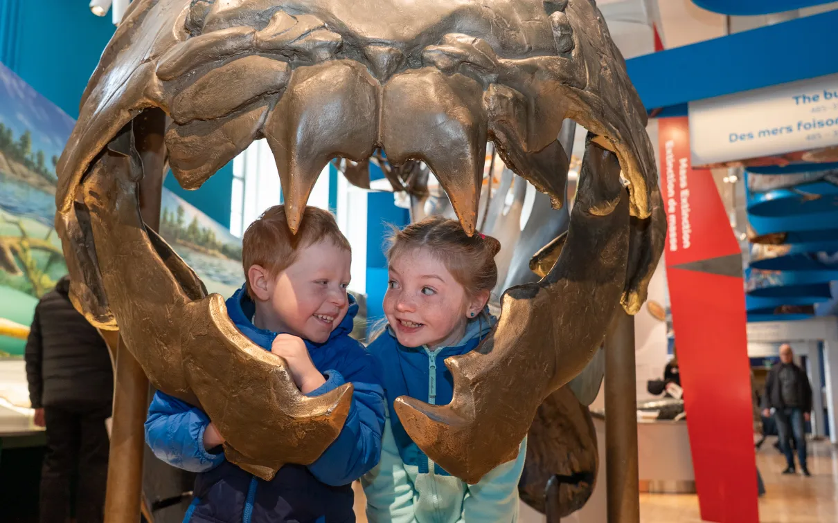 Two children look out from the mouth of the Dunkleosteus in the Dawn of Life Gallery