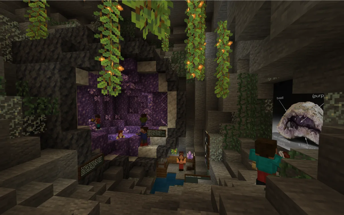 A Minecraft screenshot of a large amethyst and calcite geode. Small Minecraft characters walk around the geode, and a large labelled poster of a real geode is on the wall.