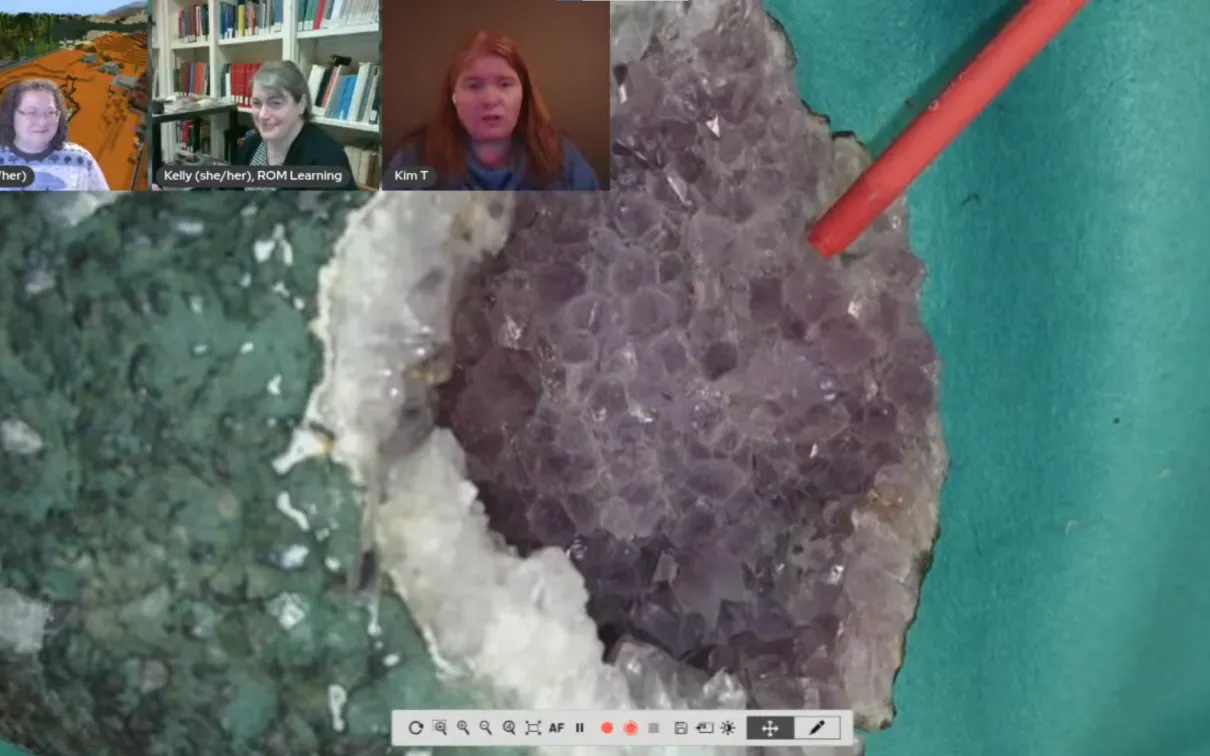 A desktop camera shows a sparkling geode with a greenish basalt exterior and a purple crystal interior.
